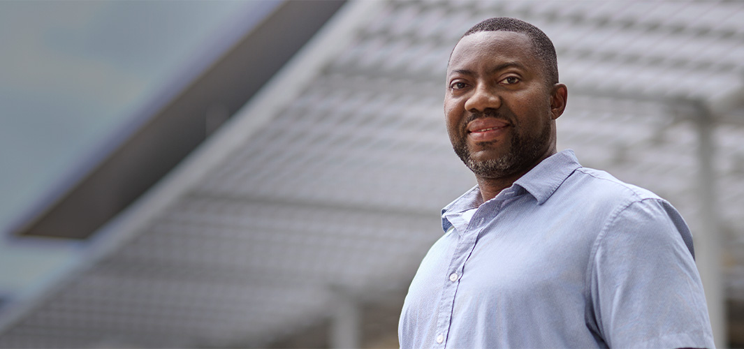 Kofi a szabadban áll, és mosolyogva néz a kamerába.