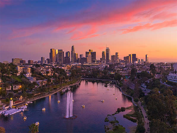 Luftaufnahme mit Blick auf die Wolkenkratzer von Los Angeles mit einem Park und See im Vordergrund.