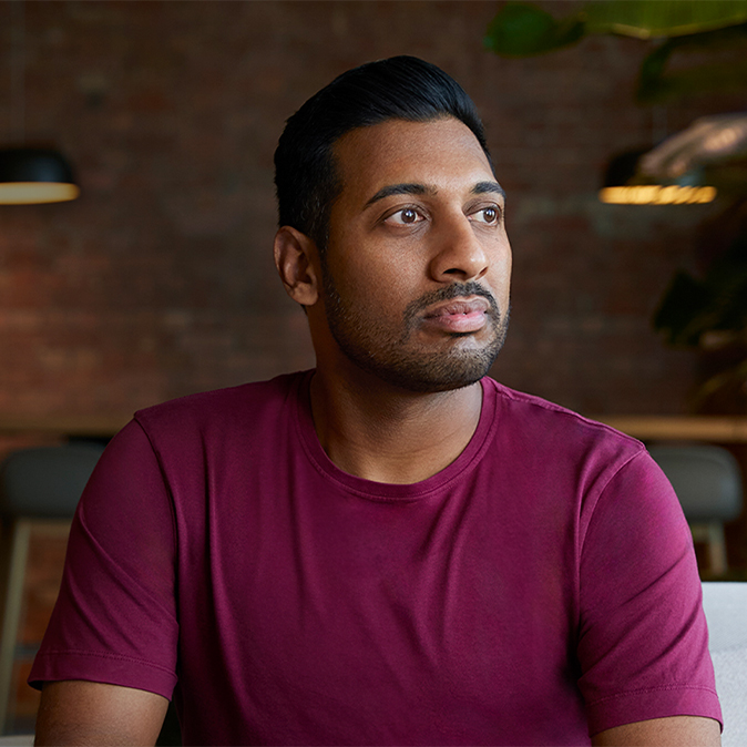 屋内で座り、自身の左側を見つめるアマー。