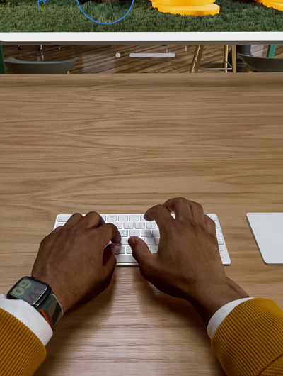 Zwei Hände über einem Magic Keyboard