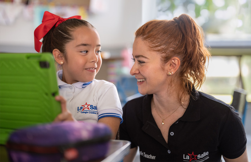 Eleane Ruth Guzmán Padilla y una de sus alumnas en un salón de clases del Colegio Cristóbal Colón.