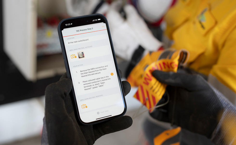 Handen houden een iPhone vast die instructies weergeeft om een schakelbordtest uit te voeren, met de woorden ‘13C Proces Stap 3’ op het scherm