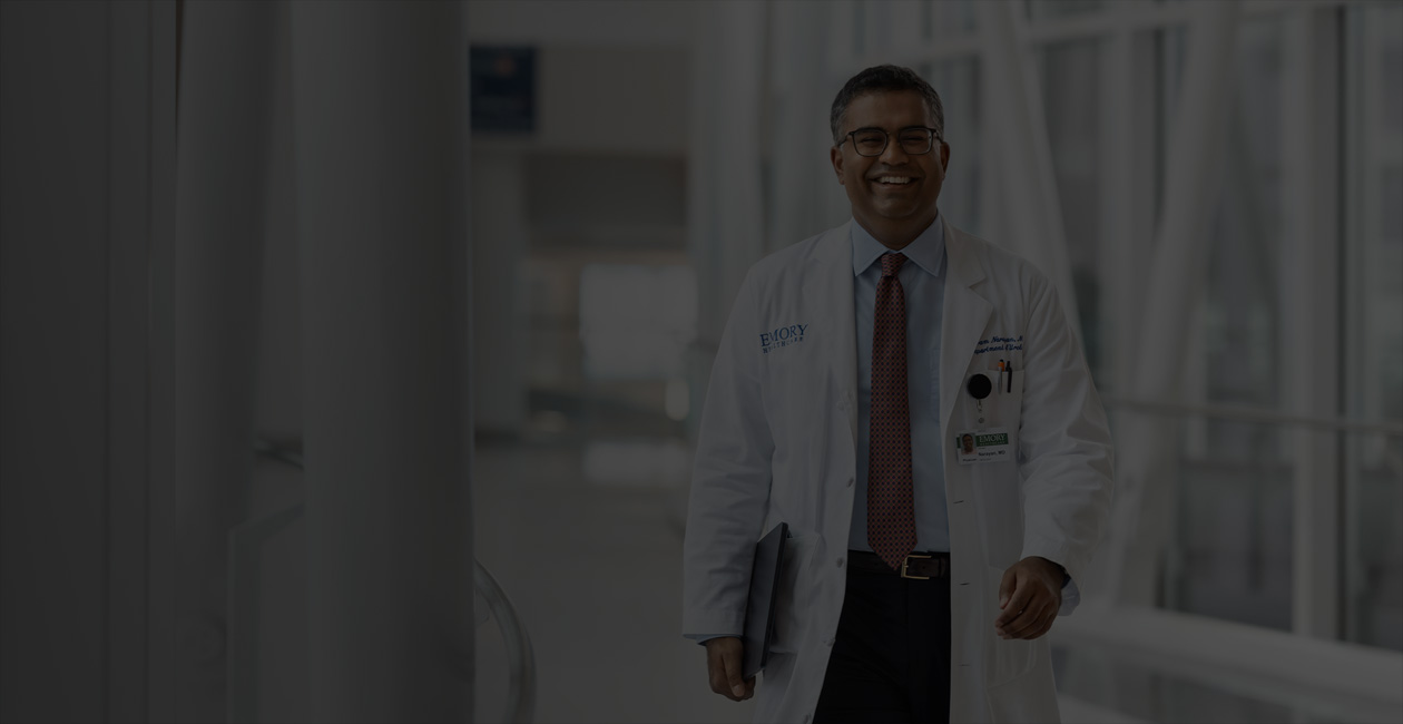 一個醫生正在行走，右手拿著一部 MacBook。 