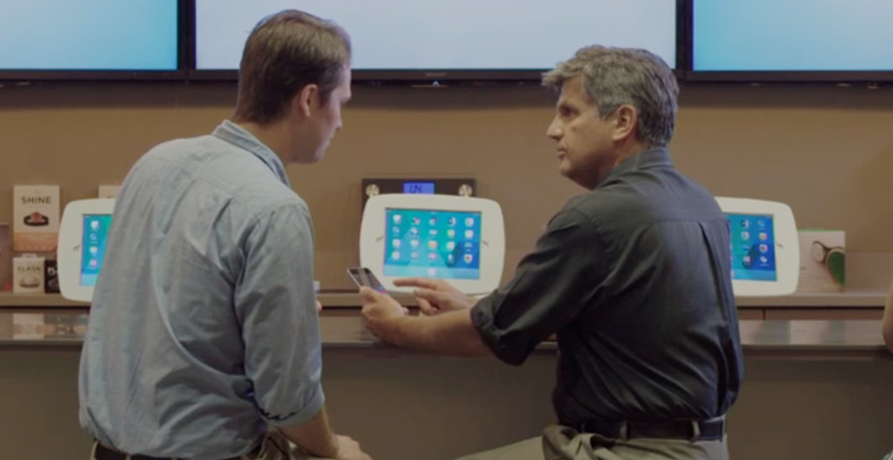 Two men sitting at the O Bar, looking at an iPhone screen.